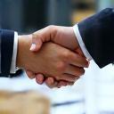 Two hands shaking over a table with documents, symbolizing agreement